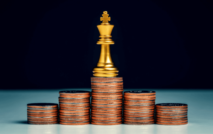 A Chess King piece is sitting on top of a pyramid of coins to symbolize 'cash is king'.