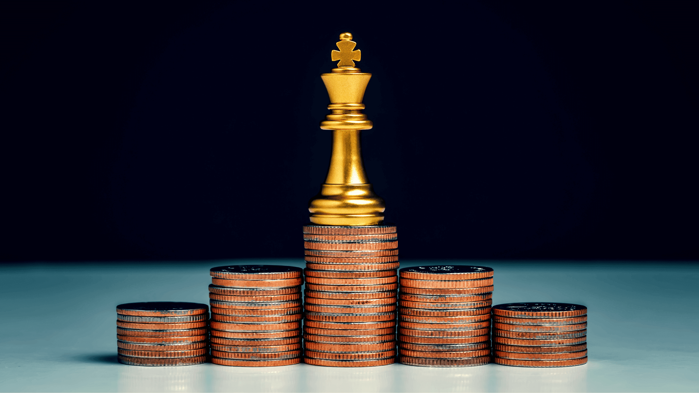 A Chess King piece is sitting on top of a pyramid of coins to symbolize 'cash is king'.