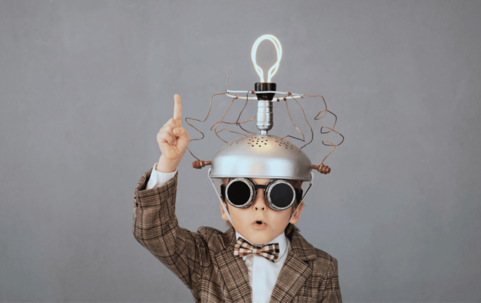 Kid genius wearing a metal handmade idea hat with lightbulb. His face looks like he is saying "I have an idea". Our Fractional CFO geniuses can help you with your SaaS metrics.
