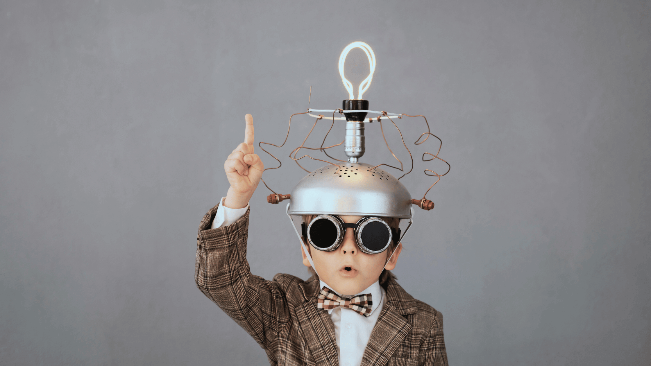 Kid genius wearing a metal handmade idea hat with lightbulb. His face looks like he is saying "I have an idea". Our Fractional CFO geniuses can help you with your SaaS metrics.